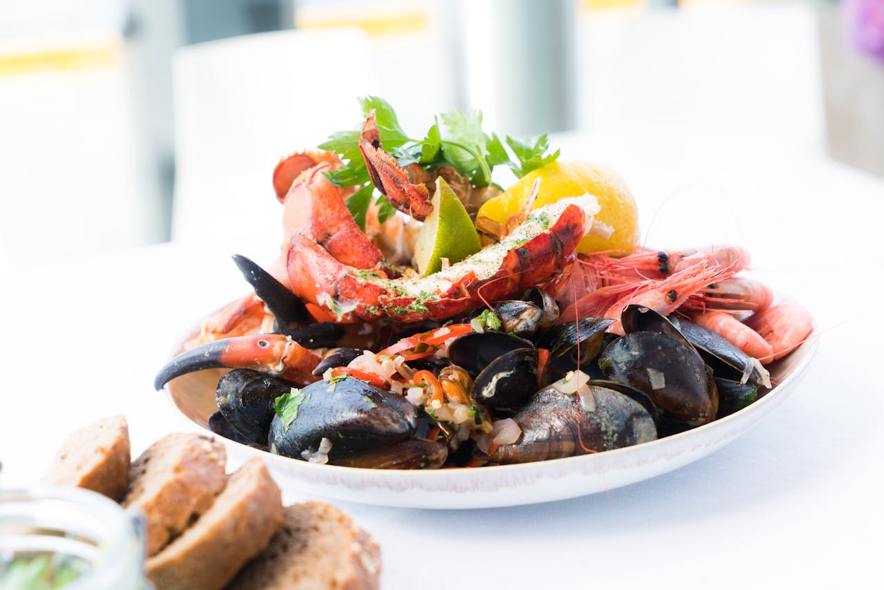 A vibrant seafood platter featuring lobster, shrimp, mussels, and lemon on a white plate.