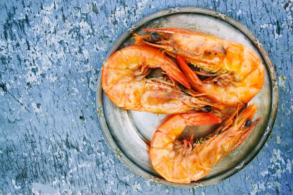 Top view of cooked shrimps on a metal plate on rustic surface. Perfect for seafood lovers.